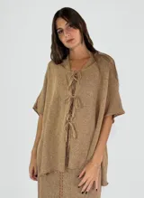 Saco tejido en hilo de lino color marrón claro, con mangas cortas y lazos frontales para atar. Diseño holgado y textura rústica.