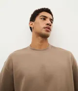 Remera de corte oversize color marrón, con cuello redondo, mangas cortas y sisa desplazada. Diseño liso sin estampados.