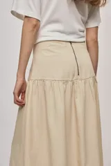 Falda midi de denim color beige, con diseño de volados y caída fluida.