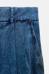 Pantalón de jean estilo bombacho con tiro medio, confeccionado en denim azul con costuras verticales decorativas y puños ajustados en el ruedo.