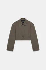 Blazer corta de corte recto con estampado de cuadros pequeños en tonos marrones y negros. Presenta cuello solapa, manga larga y cierre frontal con un botón.