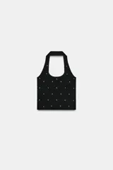 Top de punto negro con cuello halter y escote redondo, decorado con tachas metálicas plateadas distribuidas por toda la prenda.