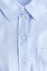 Camisa de manga larga en tejido liviano de mezcla de lino y viscosa, color celeste, con cuello clásico, cierre frontal de botones, bolsillo superior en el pecho y bajo redondeado.