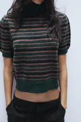 Jersey de punto con cuello subido y manga corta, diseño a rayas horizontales en tonos verde oscuro, negro y rosado.