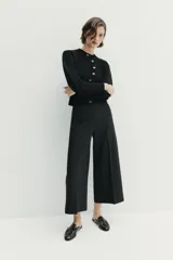Pantalón culotte negro de tiro alto con bolsillos delanteros, pernera ancha y corta, y raya marcada al frente. Cuenta con cierre lateral con cremallera oculta.