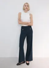 Pantalón azul marino de tiro medio y corte flare, con bolsillos frontales decorados con botones dorados.