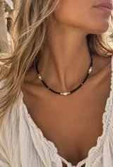 Collar corto de cuentas negras con perlas cultivadas y pequeños separadores dorados.