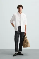 Camisa celeste a rayas verticales, de corte relaxed fit, confeccionada en lino y algodón. Tiene cuello abotonado, manga larga con puños abotonados, bolsillo de parche en el pecho y cierre frontal con botones.