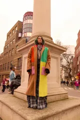 Tapado largo de paño con diseño color block en tonos marrón, verde, amarillo y naranja. Presenta solapas, bolsillos de parche en contraste rosa y un corte recto.