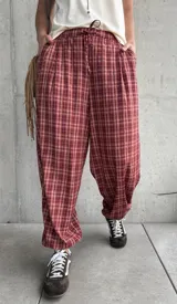 Pantalón estilo babucha color rojo con estampa a cuadros, tiro medio y cintura elástica con cordón ajustable.