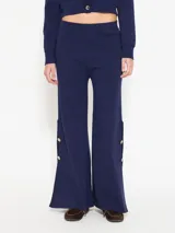 Pantalón azul de hilado frío, tejido cerrado y pesado, largo a los tobillos, con botones dorados en los laterales.