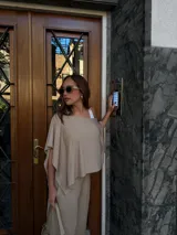 Blusa de lanilla color beige, con diseño de un solo hombro y corte holgado tipo capa.