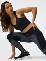 Top deportivo negro con cortes y pespuntes inspirados en la época victoriana y diseño de estética corsetera, que ofrece sujeción alta.