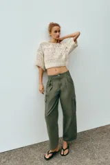 Top cropped de punto con diseño combinado de texturas, cuello redondo y mangas cortas amplias. Presenta una estructura calada con detalles de cintas verticales.