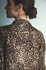 Pijama de dos piezas con estampado animal print de leopardo. Incluye una camisa de manga larga con cuello camisero y cierre frontal de botones, y un pantalón de corte recto y holgado con cintura elástica.