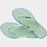 Ojotas Havaianas modelo Slim Point, con suela y tiras más finas, punta ligeramente puntiaguda y borde contrastante. Las tiras son de color lila claro con el logotipo de Havaianas en metalizado. La suela es lila claro con borde exterior en color terracota/rosado oscuro.