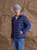Campera puffer de plumas en color azul marino, con cierre frontal, cuello alto y bolsillos laterales. Presenta un diseño acolchado horizontal y un pequeño parche distintivo en la manga.