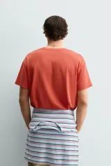 Camiseta de corte relajado con cuello redondo y manga corta. Presenta un estampado frontal con texto en contraste y un acabado con efecto lavado que le otorga una apariencia única.