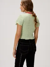 Remera baby-tee a rayas verde y blanca con cuello redondo rojo y gráfico impreso en la parte delantera, de manga corta y textura fruncida.