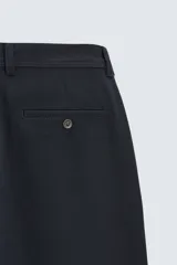 Pantalón chino de corte slim fit, confeccionado en tejido elástico. Presenta bolsillos frontales, bolsillos traseros de vivo con botón y cierre frontal con cremallera y botón.