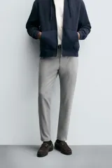 Pantalón de corte slim fit confeccionado en tejido elástico, con cintura elástica, cierre frontal con cremallera y botón, bolsillos laterales y bolsillos traseros de vivo.