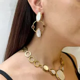 Aretes colgantes de bronce con diseño geométrico y engarce de piedras naturales. Presentan dos óvalos grandes de piedra turquesa, dos piedras redondas rojas y dos piedras redondas de ojo de tigre, unidos por aros de bronce.