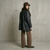 Chaqueta de cuero con acabado texturizado, corte recto y largo medio. Presenta cuello camisero, cierre frontal con cremallera y solapa con botones a presión, bolsillos laterales con solapa y puños ajustables con trabillas.