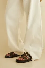 Sandalias negras de cuero con tiras cruzadas y ajuste con hebilla. Decoración de tachas plateadas en la suela.