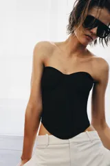 Top tipo corsé negro de Zara Woman Collection, confeccionado en hilatura con mezcla de algodón, con escote corazón y aros. Presenta bajo asimétrico y cierre en la espalda con ganchos metálicos.