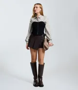 Short pollera de estilo sastre con diseño de plegado delantero, cintura estructurada y cinturón lateral integrado con hebilla metálica.