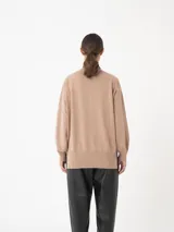 Sweater azul de cuello alto, con mangas amplias y puños ajustados.