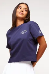 Remera blanca de algodón con corte crop, mangas cortas y estampado frontal con texto y logo en color gris.