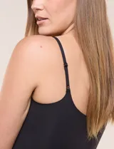 Top crop ajustado negro de estilo corsé, con tirantes finos regulables y escote corazón. Cuenta con costuras verticales decorativas en el frente.