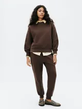 Buzo color crema de algodón, de corte holgado, con cuello redondo y mangas largas. Puños y ruedo acanalados.