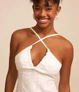 Mono largo blanco de sarga con escote en pico, tirantes finos, lazo en la espalda y cierre con cremallera.