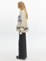 Sweater de lana color crema con diseño geométrico en azul y negro. Tiene cuello redondo y corte holgado.