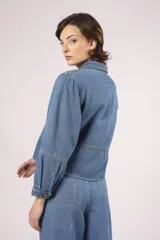 Camisa de denim celeste, de corte cropped, con cuello camisero, mangas 3/4 abullonadas y cierre frontal con botones.