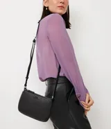 Bolso baguette pequeño color negro, con correa transversal ajustable y bolsillo interno con cremallera. Textura tipo saffiano y cierre por cremallera.