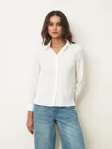 Camisa de corte clásico y manga larga, con cuello camisero y cierre frontal de botones. Presenta un diseño minimalista y versátil.