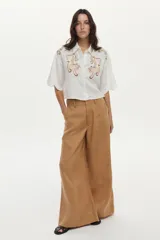 Pantalón tostado de corte wide leg, tiro alto y diseño fluido con bolsillos laterales y pinzas frontales.