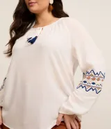 Blusa bata femenina de viscosa color blanco, con cuello redondo con lazo y borlas, manga larga con ajuste en el puño y estampa étnica en los puños.