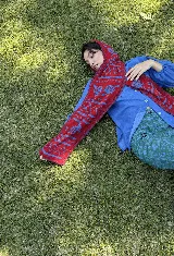 Balaclava tejida con diseño de capucha integrada y bufanda larga, confeccionada en una mezcla de algodón y acrílico con motivos geométricos en tonos rojo y azul.