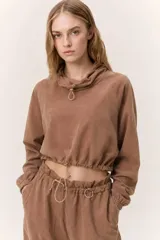 Conjunto deportivo de dos piezas compuesto por un buzo cropped de cuello alto con cordón ajustable y un pantalón estilo clochard de corte holgado con cintura elástica regulable y bolsillos laterales. Ambas prendas están confeccionadas en tejido técnico ligero con acabado suave al tacto.