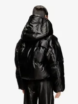 Campera puffer negra de cuero sintético con capucha y diseño acolchado, corte corto y holgado, con cierre frontal y mangas largas.
