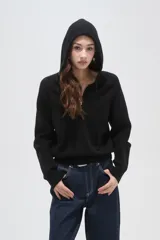 Sweater negro de punto con capucha, cierre frontal parcial y mangas largas. Presenta un diseño de tejido acanalado en la zona del cuello y los hombros.