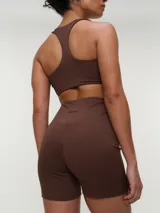 Top deportivo negro con espalda nadadora, copas removibles y detalle de logo sutil en el elástico inferior.