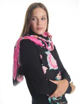 Pashmina estampada con diseño floral en tonos rosados, fucsias y verdes sobre fondo negro. Presenta terminaciones desflecadas en los bordes y está confeccionada en tejido ligero tipo gasa.