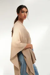 Ruana de tejido punto en color beige, con diseño amplio y caida fluida.
