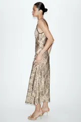 Vestido midi de estilo lencero con estampado animal print, confeccionado en tejido satinado. Presenta escote en pico tanto en el delantero como en la espalda y cuenta con doble tirante fino en color negro.
