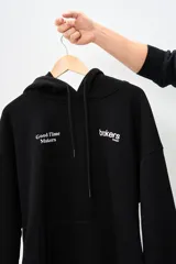 Canguro negro con capucha, cordones ajustables y bolsillo tipo canguro. Estampado frontal con el logo de la marca 'Brokers Wear' y la frase 'Good Time Makers'.